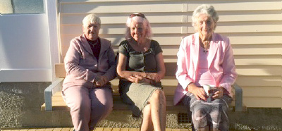 Tenants (from left) Lynley, Anthea and Kay enjoy the sunshine on the newly installed bench.